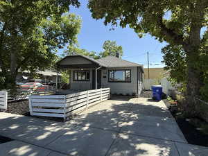 Bungalow featuring a porch, a chimney, a fenced front yard, and a shingled roof