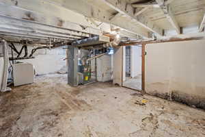 Unfinished below grade area featuring washer / clothes dryer and heating unit