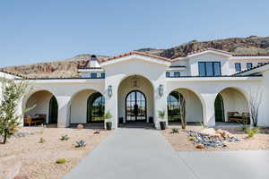 Back of property with french doors, a mountain view, and stucco siding