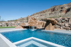 View of swimming pool featuring a pool with connected hot tub and a mountain view