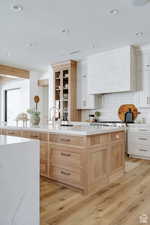 Kitchen featuring light brown cabinets, light countertops, decorative backsplash, light wood-style floors, and recessed lighting