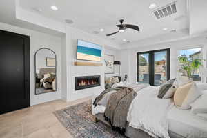 Bedroom with multiple windows, access to outside, a large fireplace, recessed lighting, and a tray ceiling