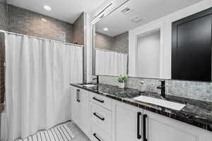 Full bath featuring double vanity, a shower with shower curtain, recessed lighting, decorative backsplash, and tile patterned flooring