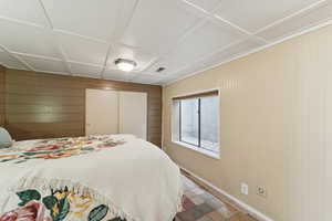 Bedroom with wooden walls, a closet, and coffered ceiling