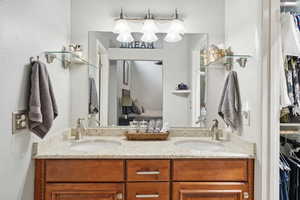Bathroom with double vanity, a walk in closet, and a textured wall