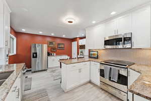 Kitchen featuring stainless steel appliances, a peninsula, tasteful backsplash, white cabinets, and recessed lighting