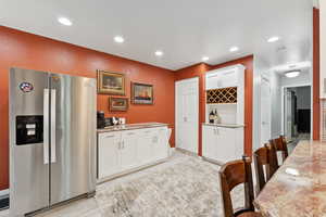 Kitchen featuring stainless steel fridge, white cabinetry, recessed lighting, light wood-style floors, and light stone countertops