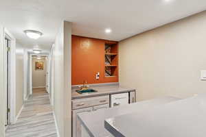 Indoor wet bar with light wood-style flooring and recessed lighting