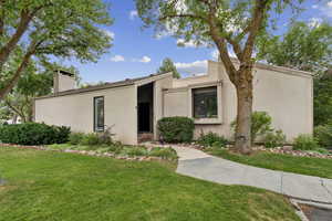 Mid-century modern home featuring stucco siding, a front yard, and a chimney