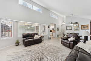 Living area with high vaulted ceiling, ceiling fan, and wood finished floors