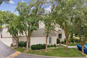 View of front of house with stucco siding, roof with shingles, a front lawn, driveway, and a garage