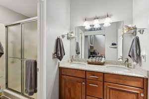 Bathroom featuring double vanity, a stall shower, and a chandelier