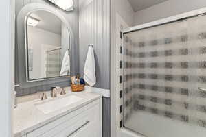 Bathroom featuring vanity and shower / bath combination with glass door