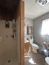 Full bath featuring a textured ceiling, a stall shower, and vanity