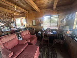 Living room featuring a wood ceiling with exposed beams and wood walls