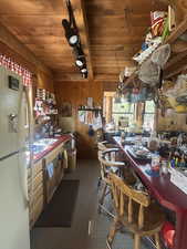 Kitchen with wood walls, freestanding refrigerator, and wooden ceiling