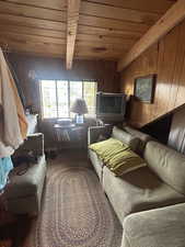 Living room with a wooden ceiling with exposed beams and wooden walls