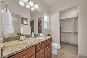 Bathroom with a walk in closet, vanity, and tile patterned floors