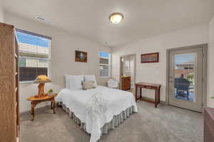 Bedroom with light carpet, access to outside, and ensuite bath