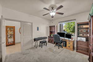 Home office with light carpet, ceiling fan, and light tile patterned flooring