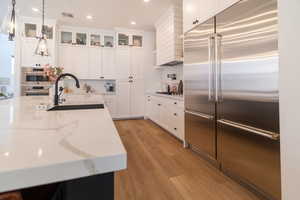 Kitchen with appliances with stainless steel finishes, decorative backsplash, light wood finished floors, white cabinets, and recessed lighting
