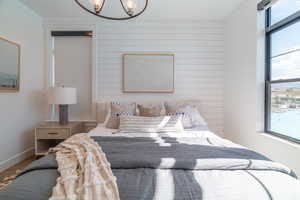Bedroom featuring a chandelier, wooden walls, and wood finished floors