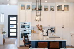 Kitchen featuring tasteful backsplash, recessed lighting, light wood-style flooring, white cabinets, and light stone countertops