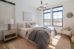 Bedroom with wood finished floors, a chandelier, and wood walls