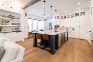 Kitchen featuring tasteful backsplash, white cabinets, open floor plan, light wood-type flooring, and recessed lighting