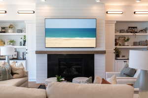 Living room featuring a fireplace, built in shelves, and wood finished floors