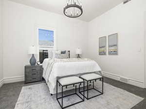 Carpeted bedroom with a chandelier and baseboards