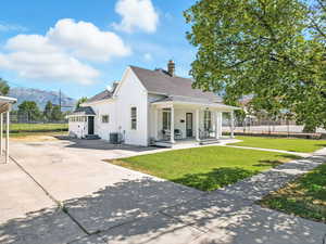 Back of property with covered porch, a chimney, and a shingled roof