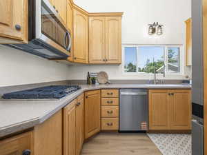 Kitchen with stainless steel appliances, light wood finished floors, and light countertops