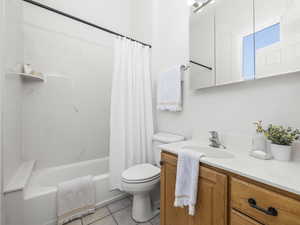 Bathroom with vanity, shower / bathtub combination with curtain, and tile patterned floors