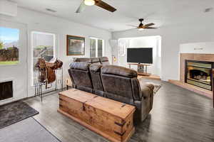 Living area with a fireplace, ceiling fan, and wood finished floors