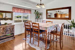 Dining space featuring wood finished floors, a chandelier, and lofted ceiling