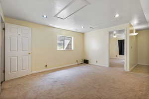 Carpeted spare room with attic access, a textured ceiling, and recessed lighting