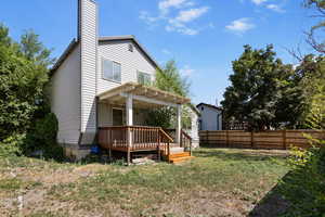 Rear view of property featuring a fenced backyard, a wooden deck, a pergola, and a chimney