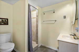 Bathroom featuring vanity, tiled shower, tile patterned flooring, and a textured ceiling