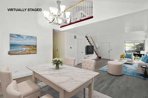 Dining room featuring a chandelier, wood finished floors, stairway, and a towering ceiling