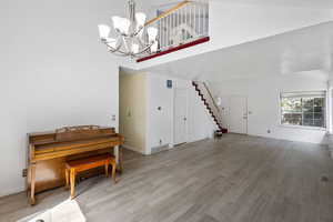 Living area featuring high vaulted ceiling, a chandelier, wood finished floors, and stairway