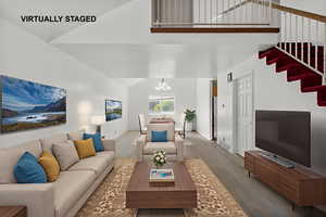 Living room with wood finished floors, a chandelier, stairway, and lofted ceiling