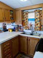 Kitchen with light countertops, brown cabinets, range, open shelves, and a peninsula