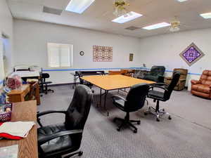 Office space with carpet flooring, a skylight, and ceiling fan