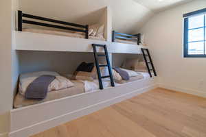 Bedroom featuring wood finished floors and vaulted ceiling