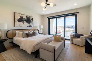 Bedroom with access to exterior, light wood-type flooring, recessed lighting, and a chandelier