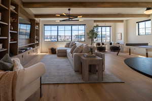 Living area with beam ceiling, wood finished floors, and a chandelier