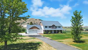 View of front of house with a garage, asphalt driveway, a front yard, and stone siding