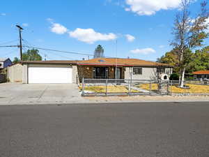 Ranch-style house featuring driveway, a fenced front yard, and a garage