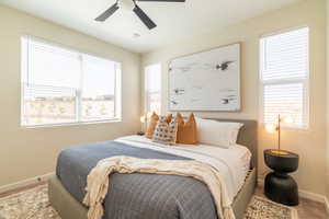 Carpeted bedroom featuring multiple windows and ceiling fan